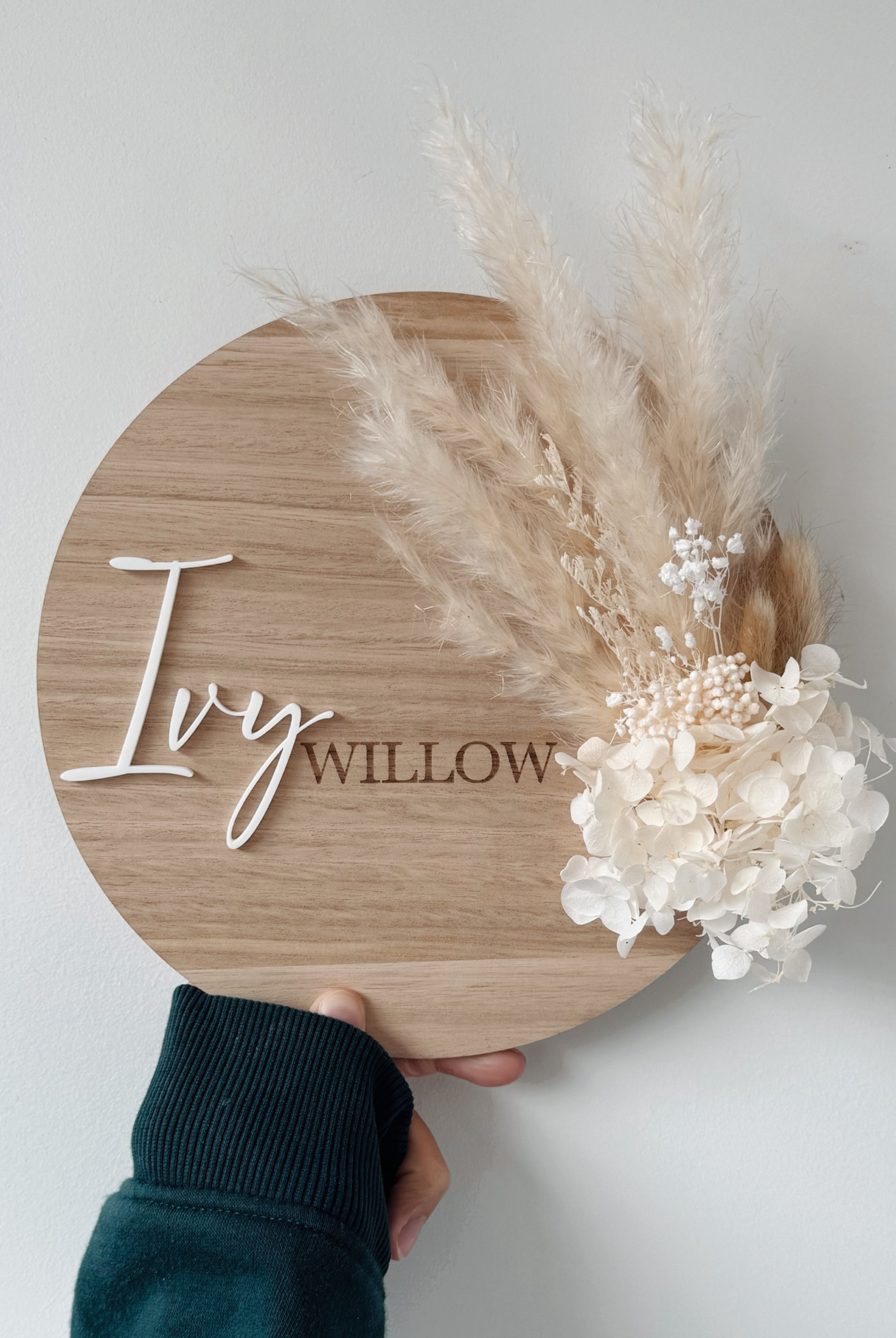 Dried floral wooden plaque with acrylic and/or laser engraved text or name, either arch or round shape, with dried preserved flowers tied to the plaque. Perfect for baby birth announcements or personalised gifts or keepsakes.