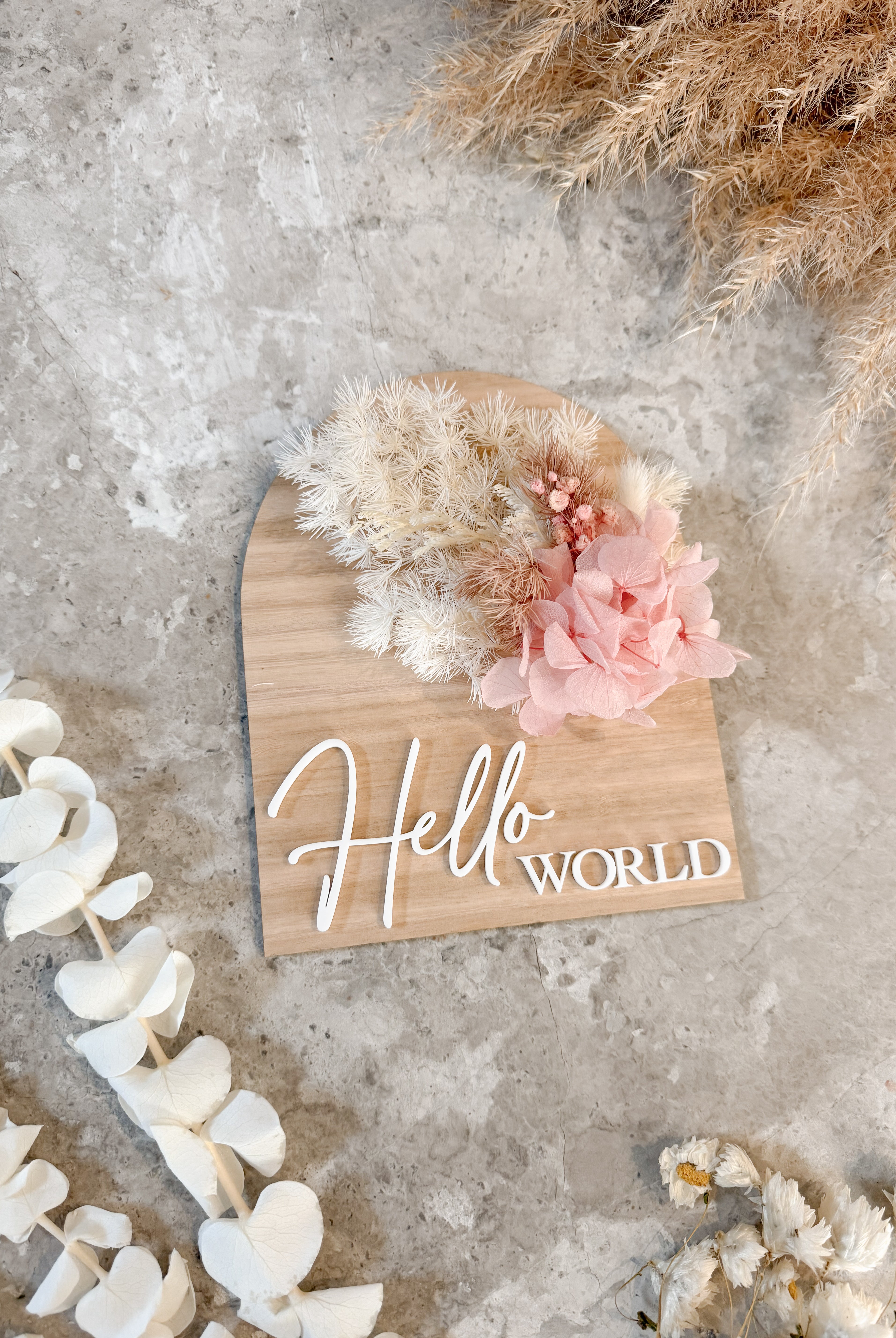 Dried floral wooden plaque with acrylic and/or laser engraved text or name, either arch or round shape, with dried preserved flowers tied to the plaque. Perfect for baby birth announcements or personalised gifts or keepsakes.