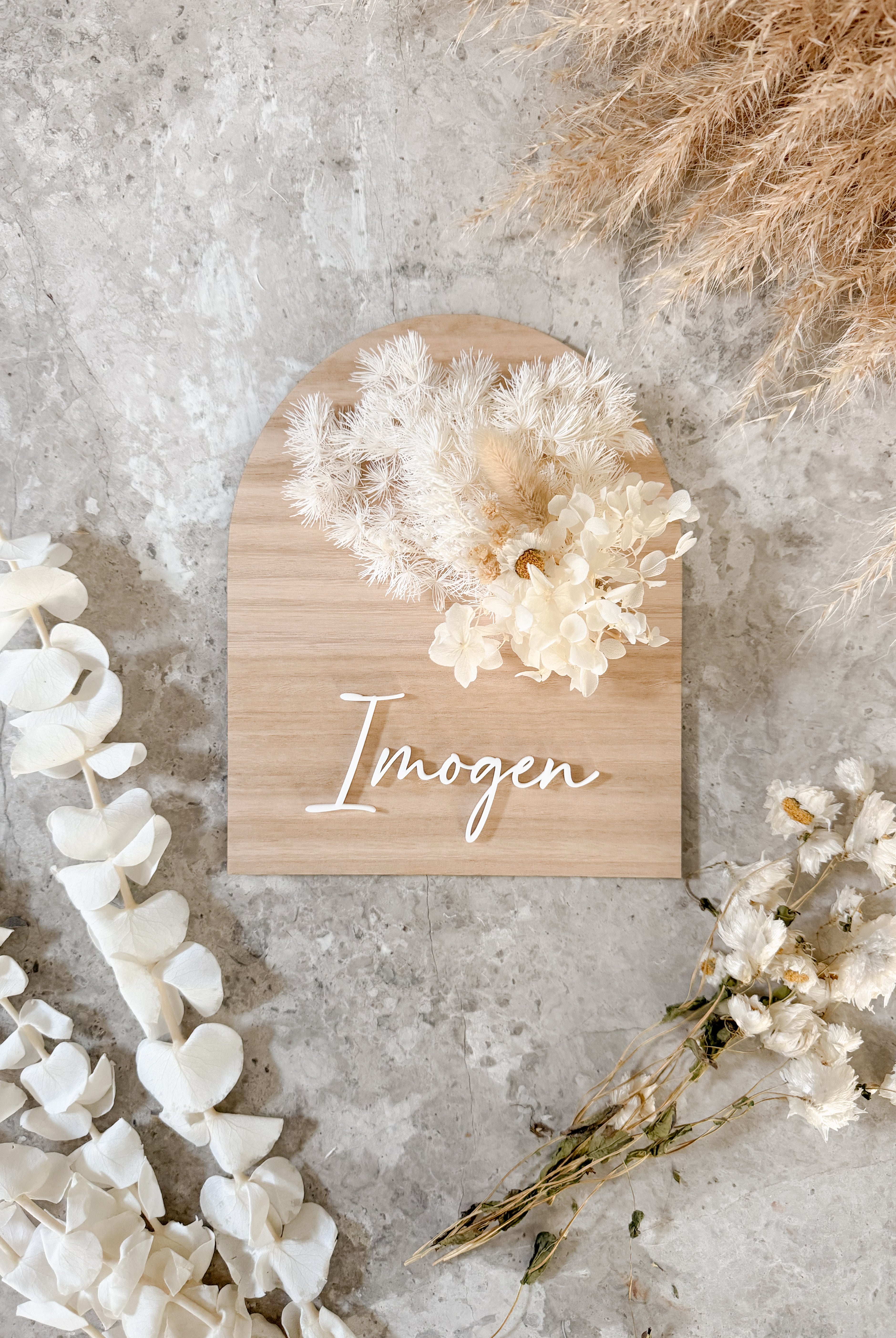 Dried floral wooden plaque with acrylic and/or laser engraved text or name, either arch or round shape, with dried preserved flowers tied to the plaque. Perfect for baby birth announcements or personalised gifts or keepsakes.