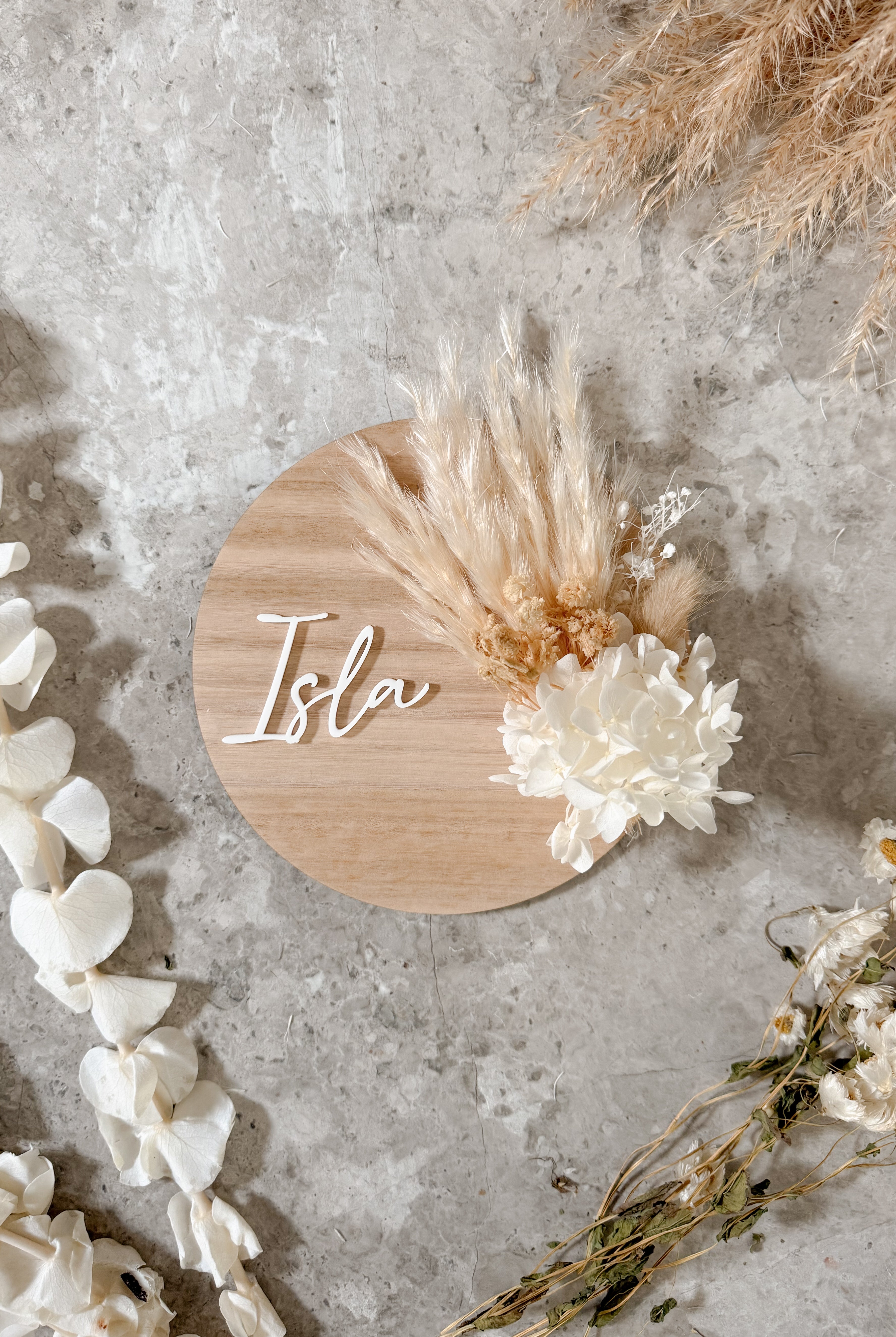 Dried floral wooden plaque with acrylic and/or laser engraved text or name, either arch or round shape, with dried preserved flowers tied to the plaque. Perfect for baby birth announcements or personalised gifts or keepsakes.