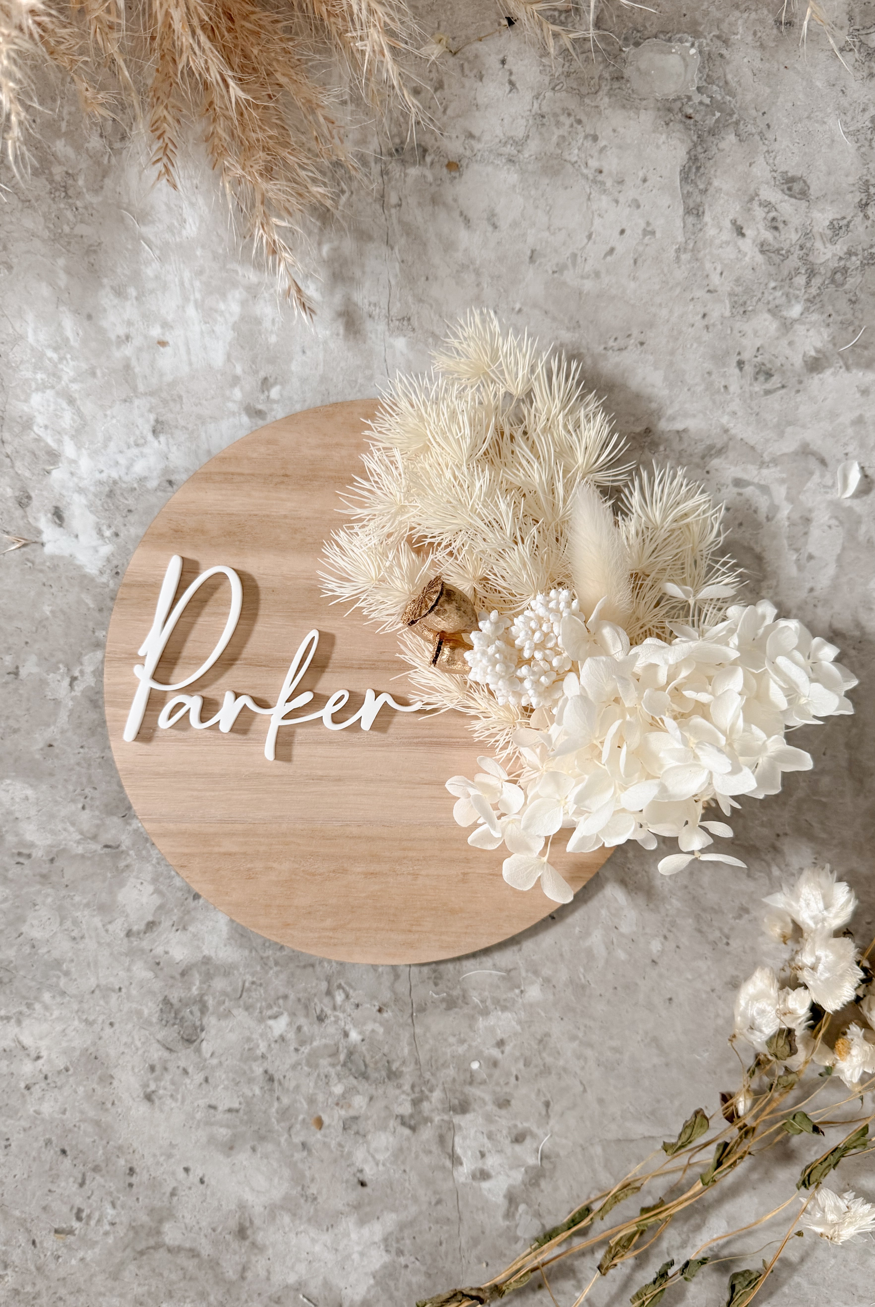 Dried floral wooden plaque with acrylic and/or laser engraved text or name, either arch or round shape, with dried preserved flowers tied to the plaque. Perfect for baby birth announcements or personalised gifts or keepsakes.