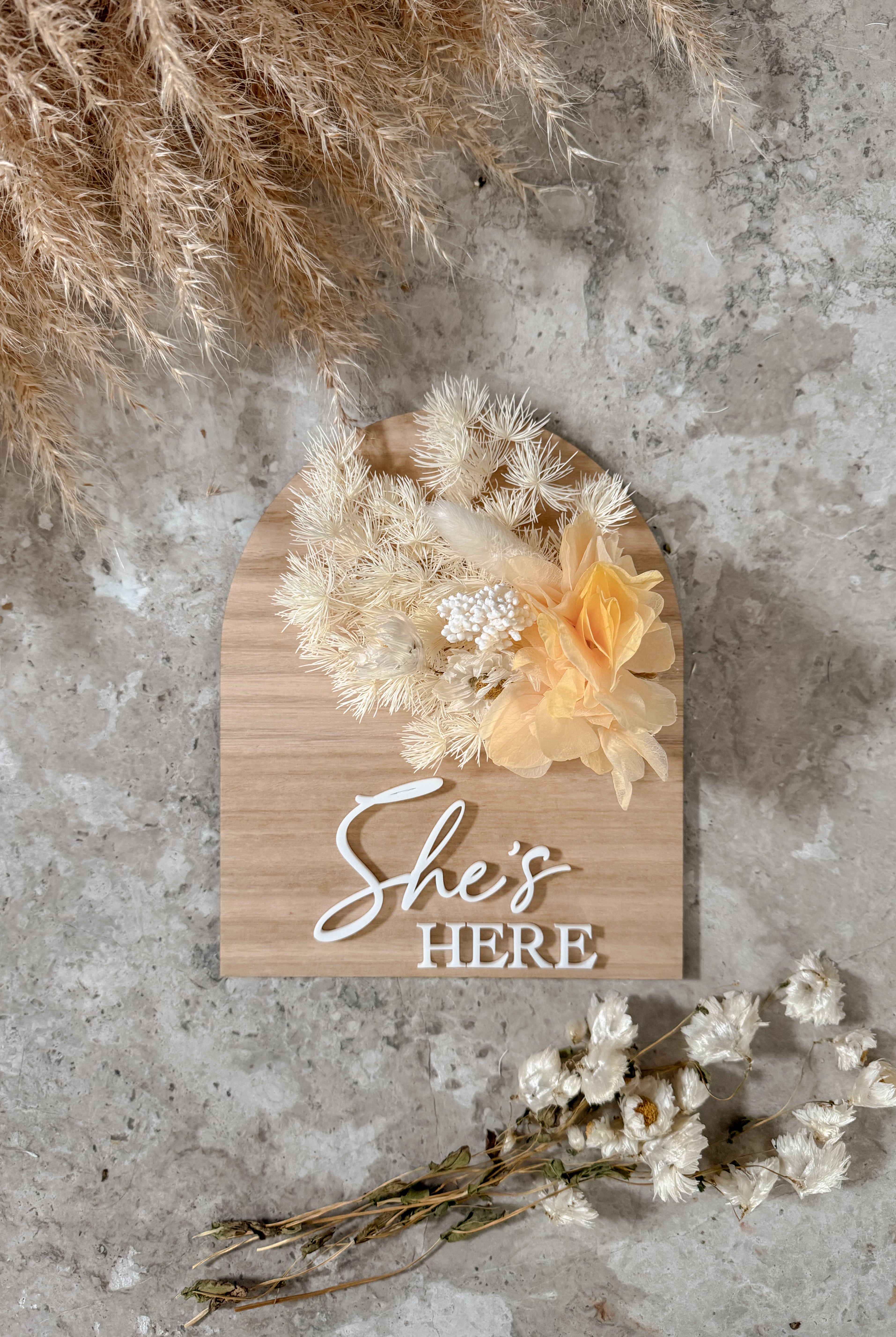 Dried floral wooden plaque with acrylic and/or laser engraved text or name, either arch or round shape, with dried preserved flowers tied to the plaque. Perfect for baby birth announcements or personalised gifts or keepsakes.