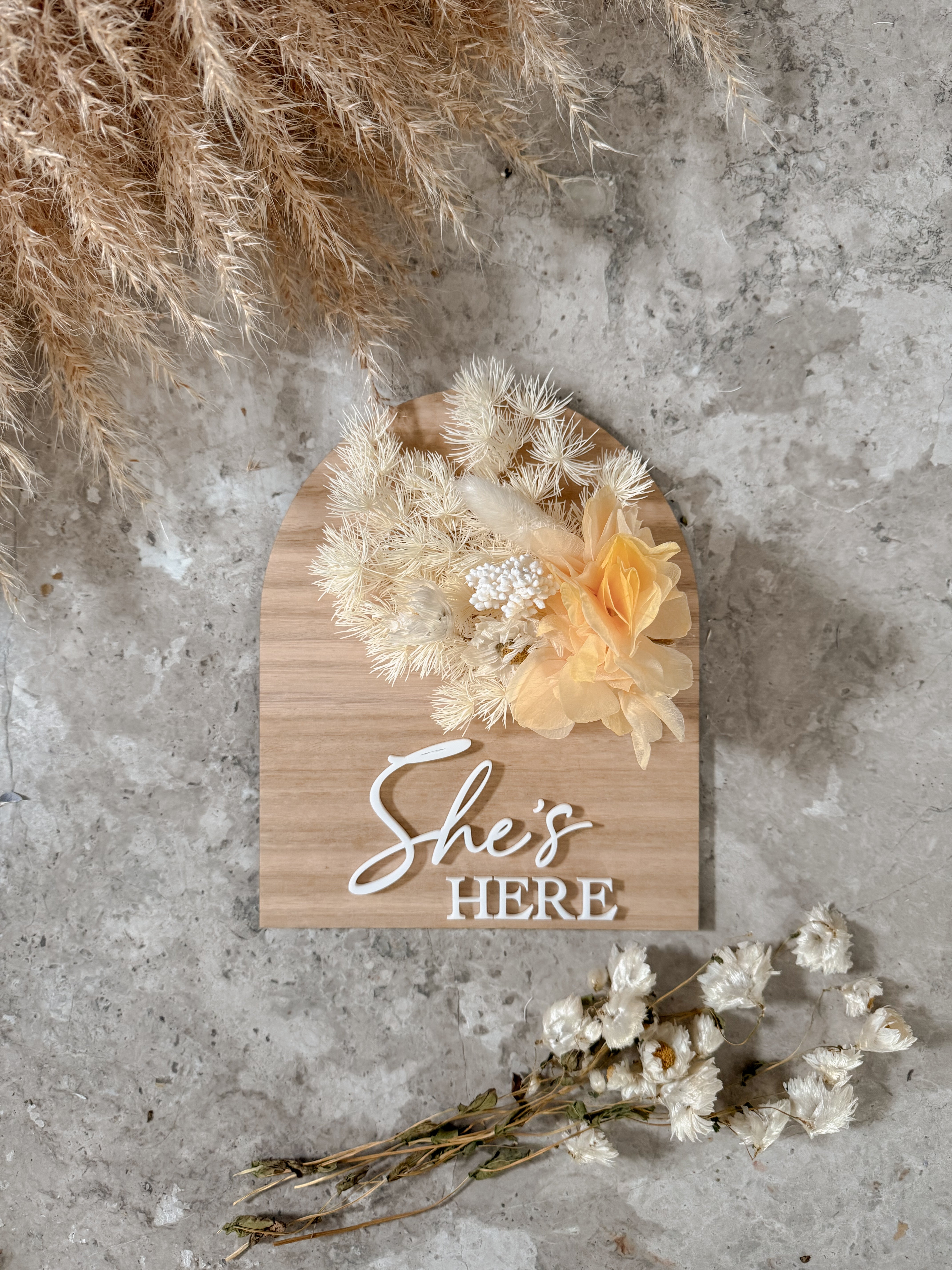Dried floral wooden plaque with acrylic and/or laser engraved text or name, either arch or round shape, with dried preserved flowers tied to the plaque. Perfect for baby birth announcements or personalised gifts or keepsakes.