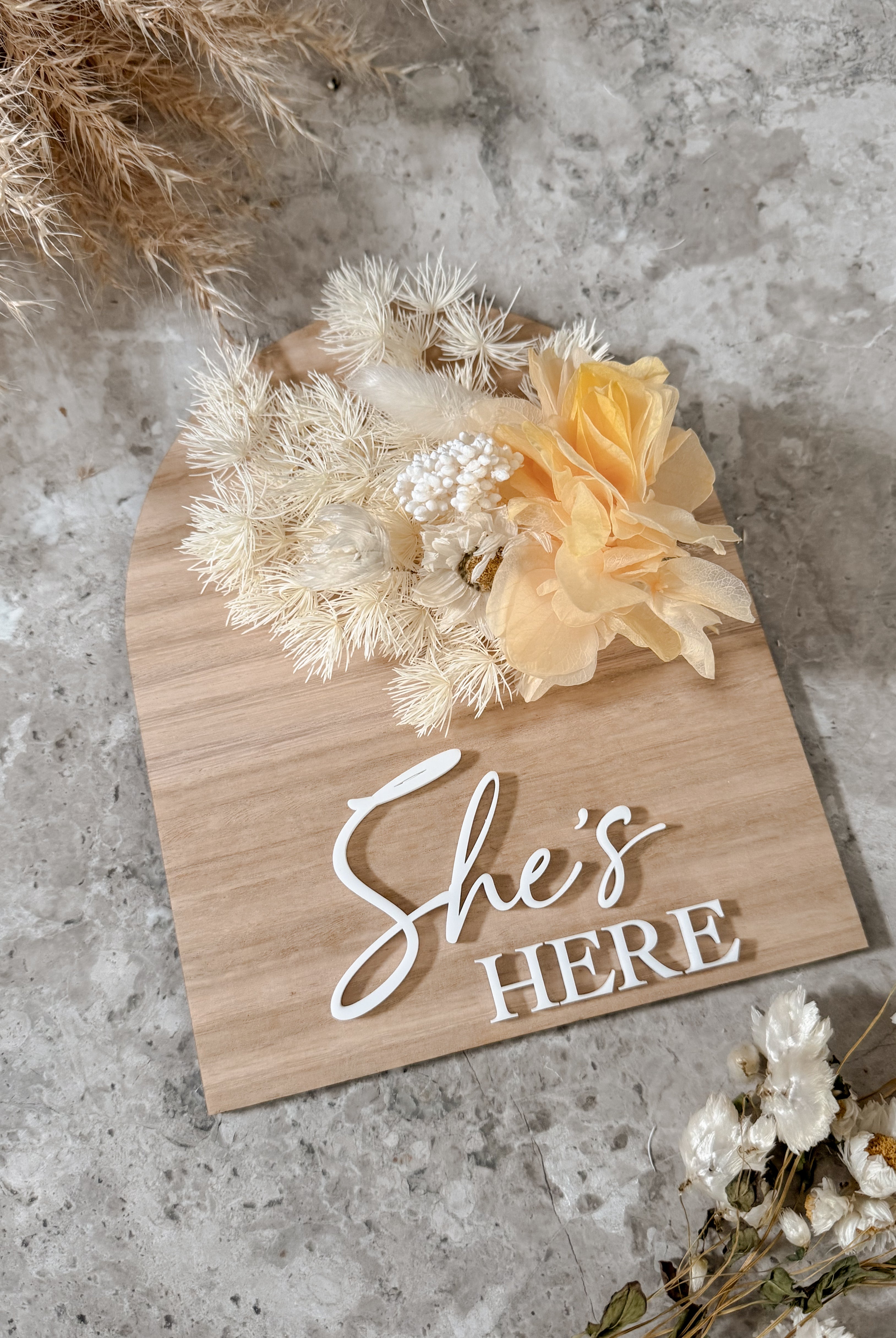 Dried floral wooden plaque with acrylic and/or laser engraved text or name, either arch or round shape, with dried preserved flowers tied to the plaque. Perfect for baby birth announcements or personalised gifts or keepsakes.