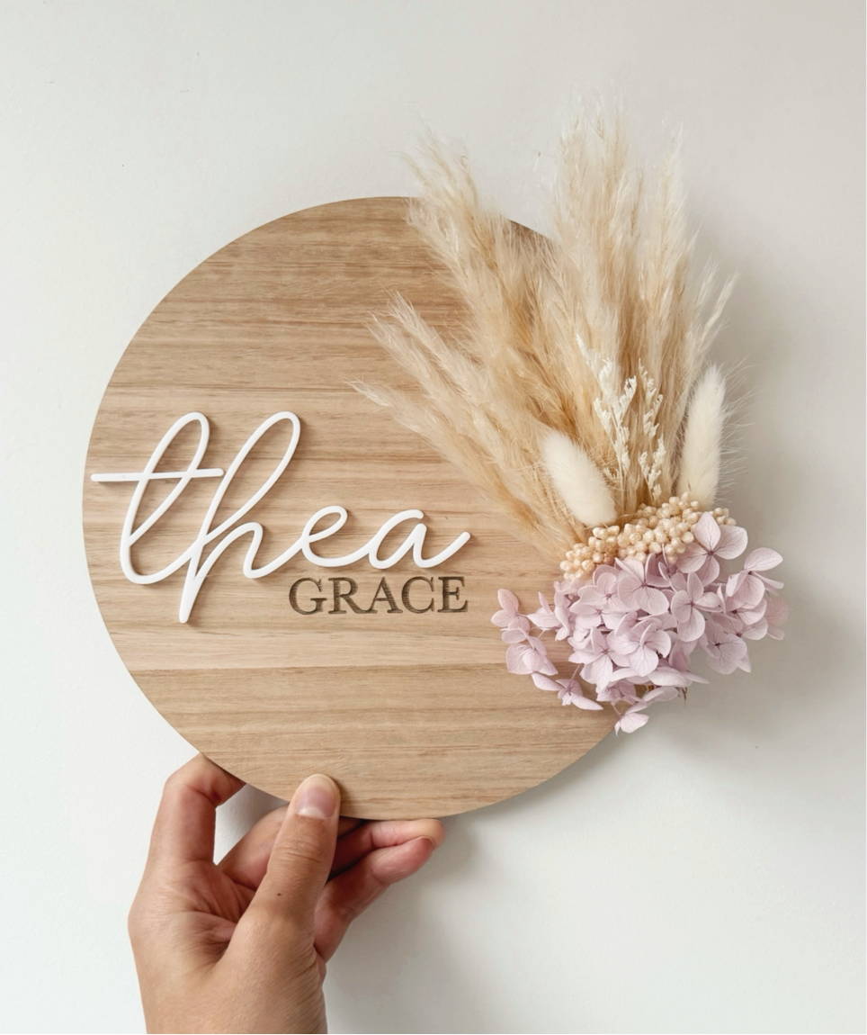 Dried floral wooden plaque with acrylic and/or laser engraved text or name, either arch or round shape, with dried preserved flowers tied to the plaque. Perfect for baby birth announcements or personalised gifts or keepsakes.