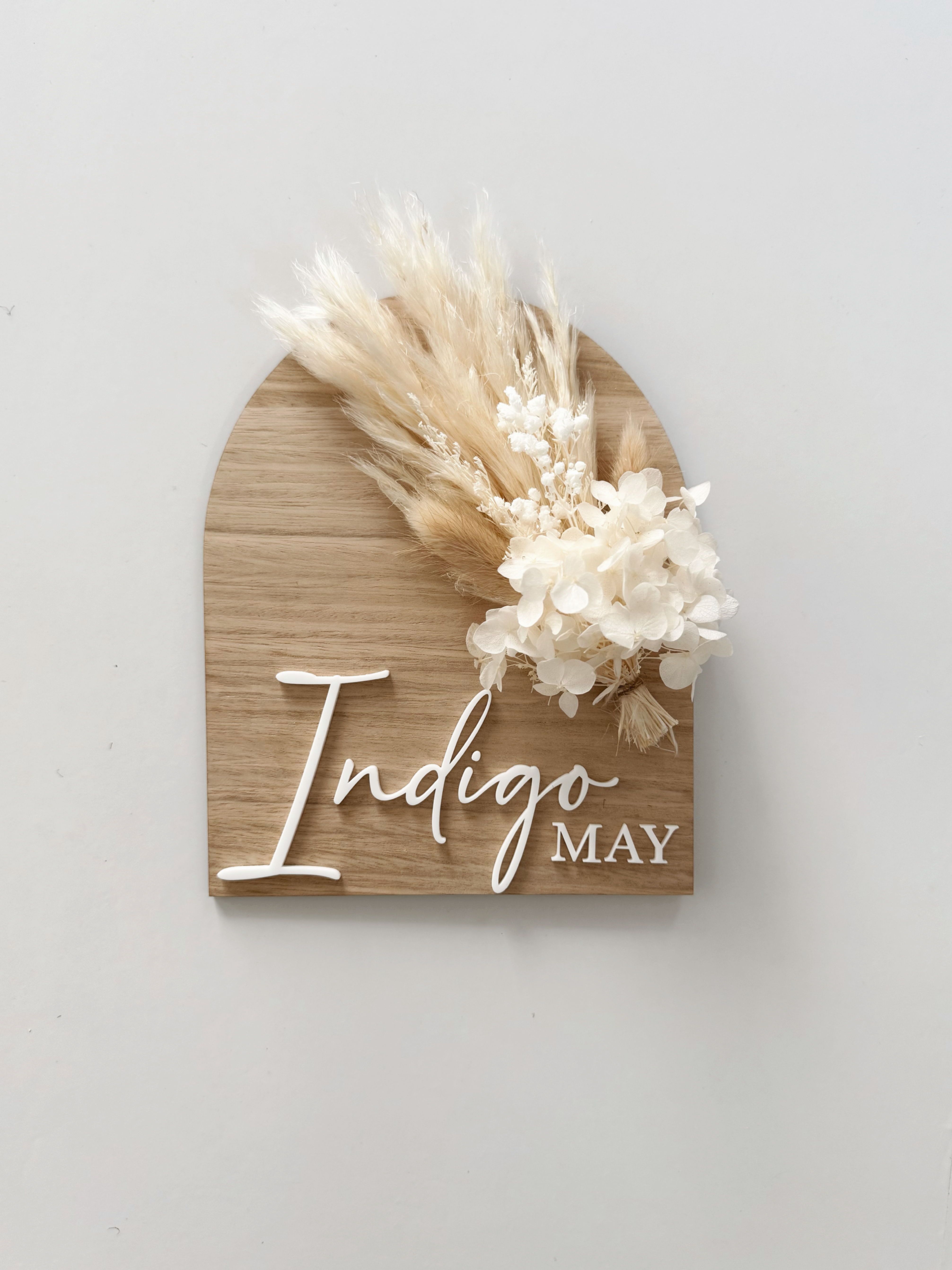Dried floral wooden plaque with acrylic and/or laser engraved text or name, either arch or round shape, with dried preserved flowers tied to the plaque. Perfect for baby birth announcements or personalised gifts or keepsakes.
