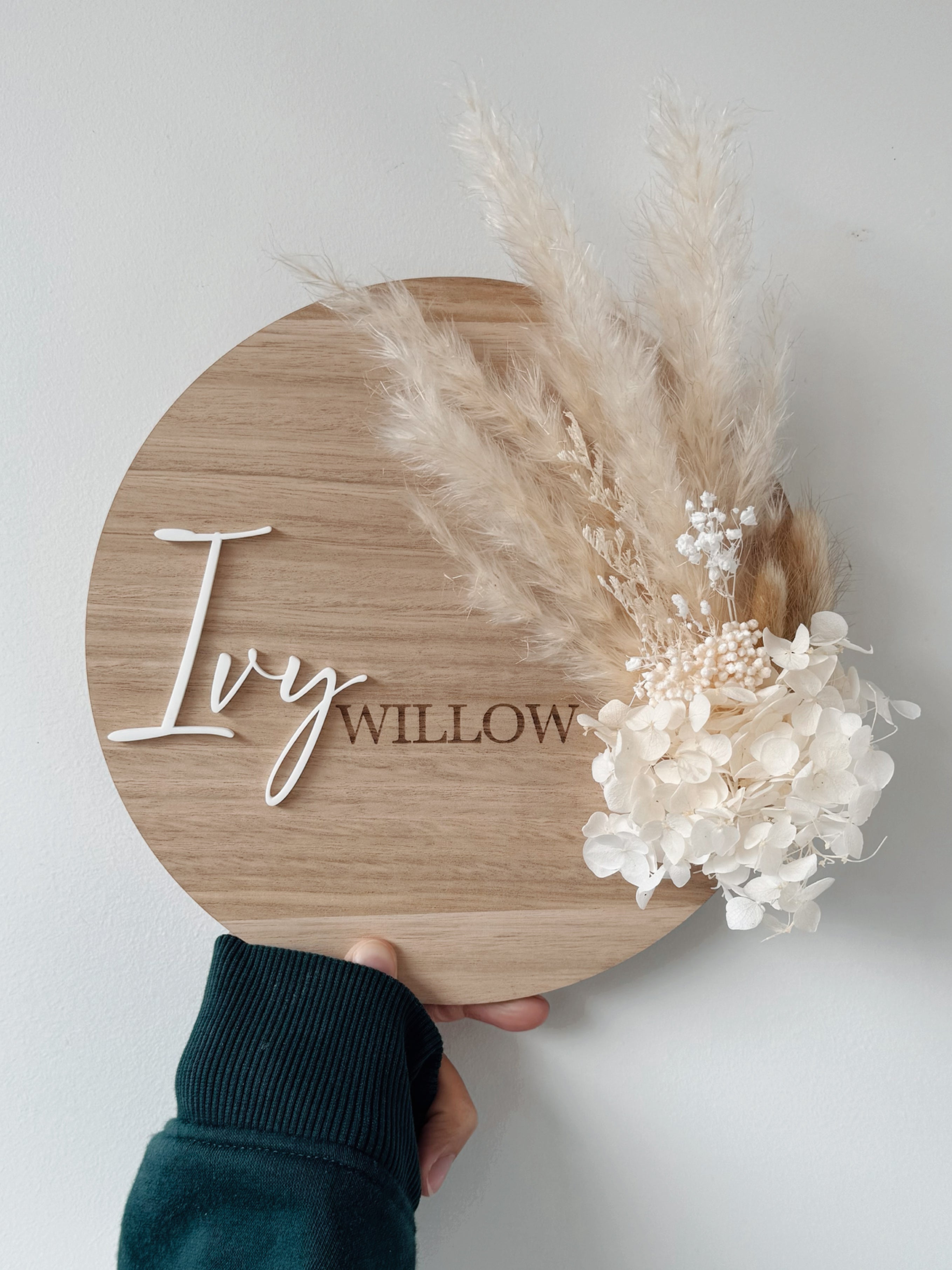 Dried floral wooden plaque with acrylic and/or laser engraved text or name, either arch or round shape, with dried preserved flowers tied to the plaque. Perfect for baby birth announcements or personalised gifts or keepsakes.
