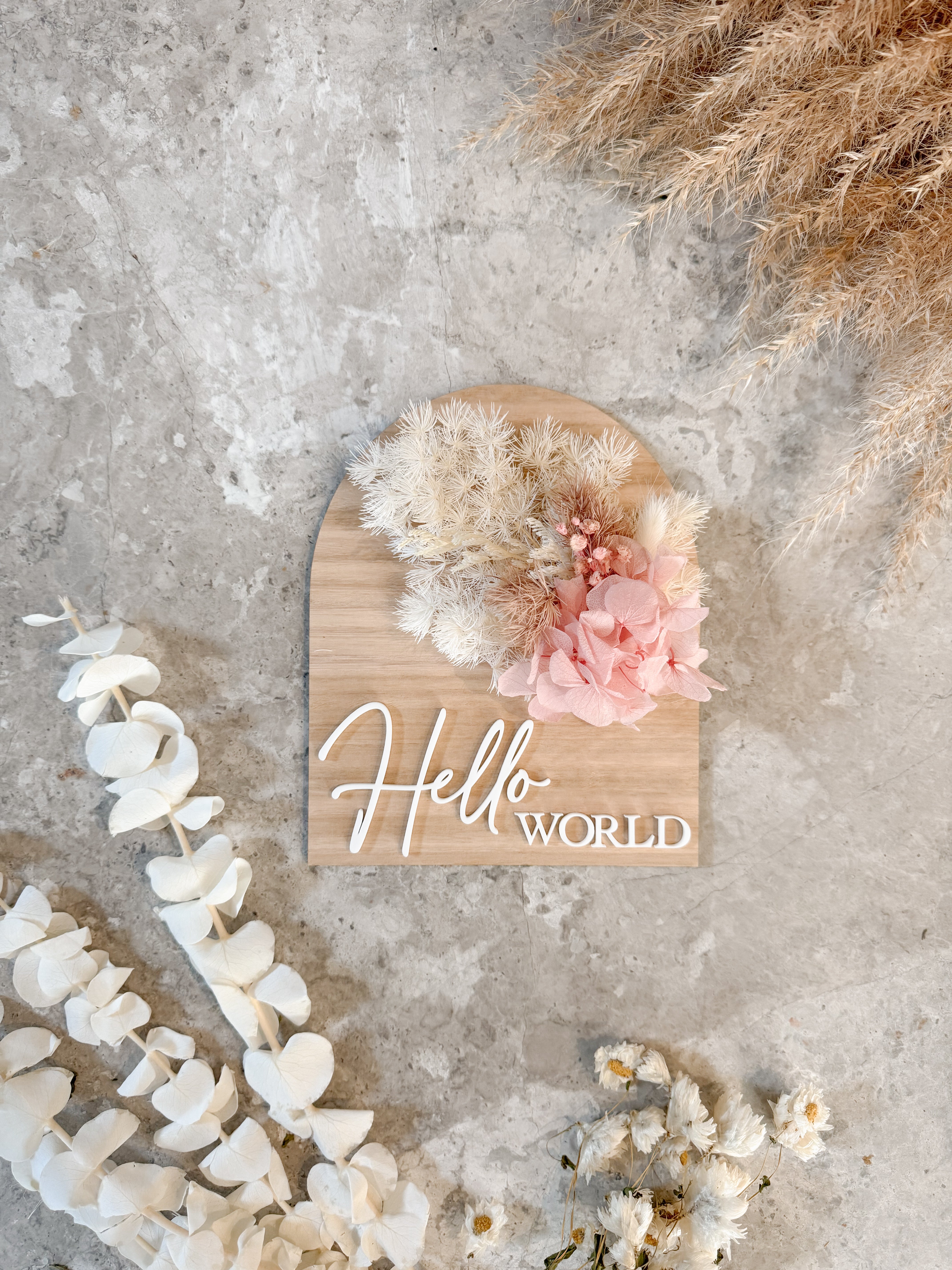 Dried floral wooden plaque with acrylic and/or laser engraved text or name, either arch or round shape, with dried preserved flowers tied to the plaque. Perfect for baby birth announcements or personalised gifts or keepsakes.