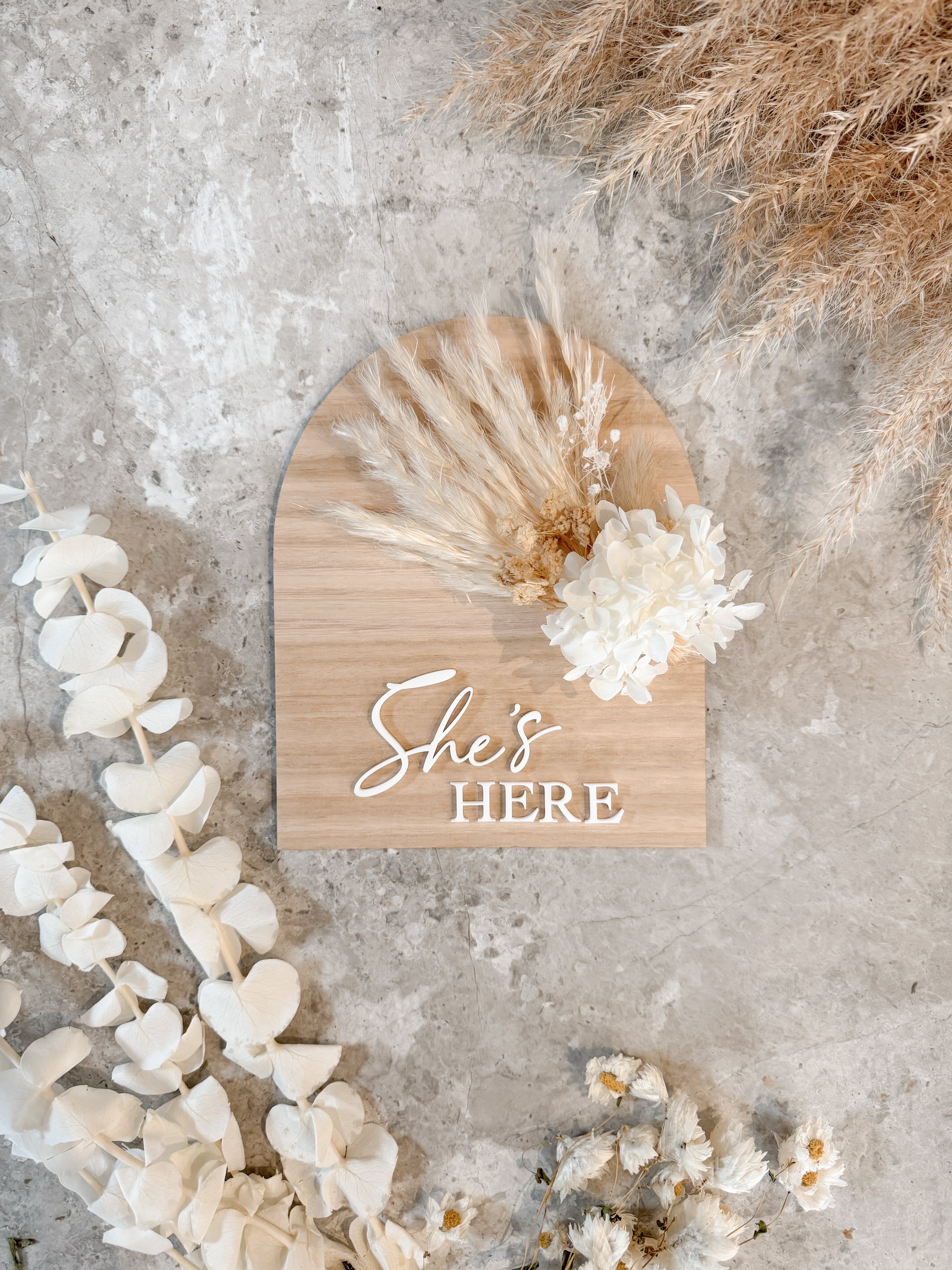 Dried floral wooden plaque with acrylic and/or laser engraved text or name, either arch or round shape, with dried preserved flowers tied to the plaque. Perfect for baby birth announcements or personalised gifts or keepsakes.