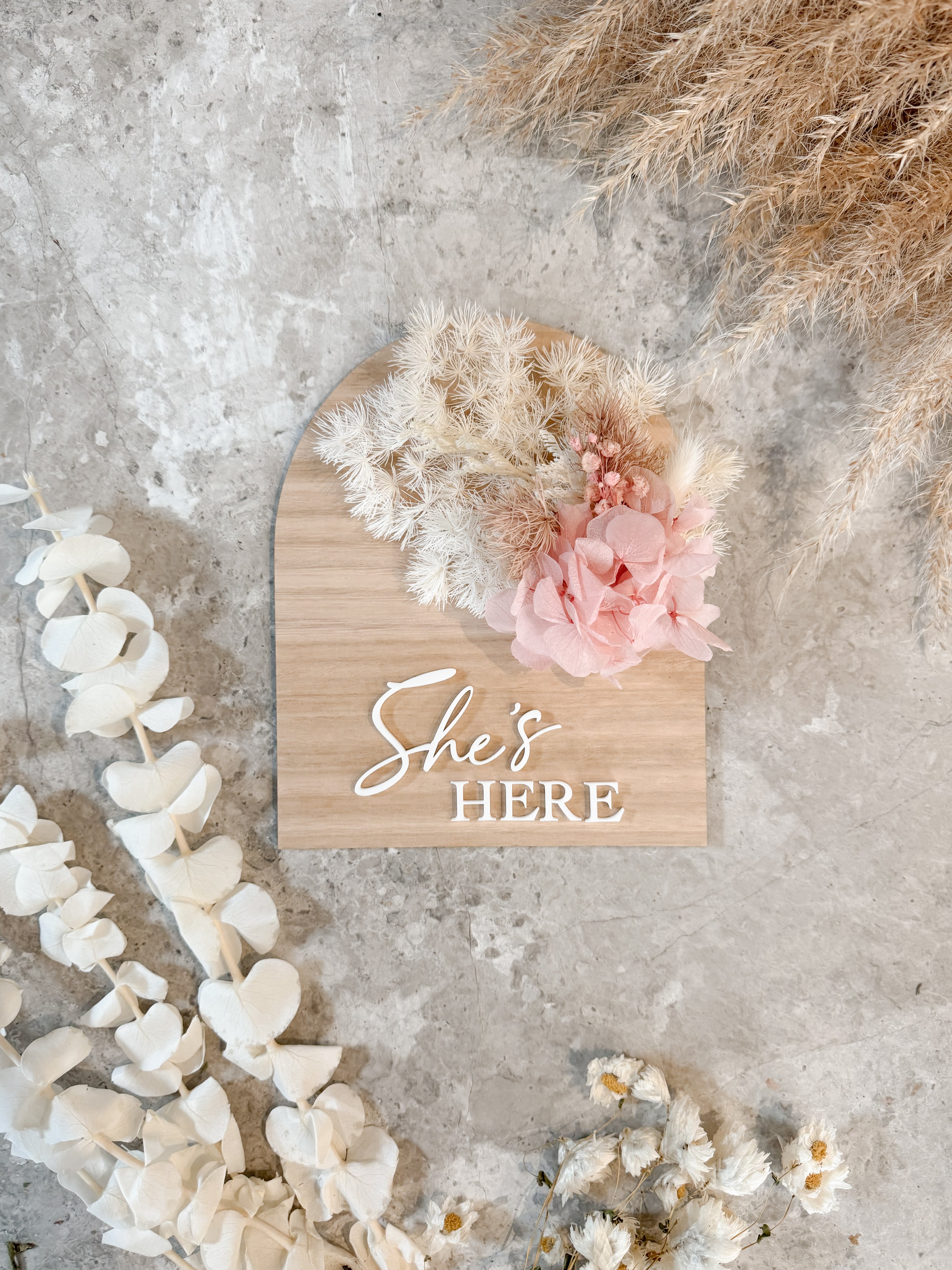 Dried floral wooden plaque with acrylic and/or laser engraved text or name, either arch or round shape, with dried preserved flowers tied to the plaque. Perfect for baby birth announcements or personalised gifts or keepsakes.