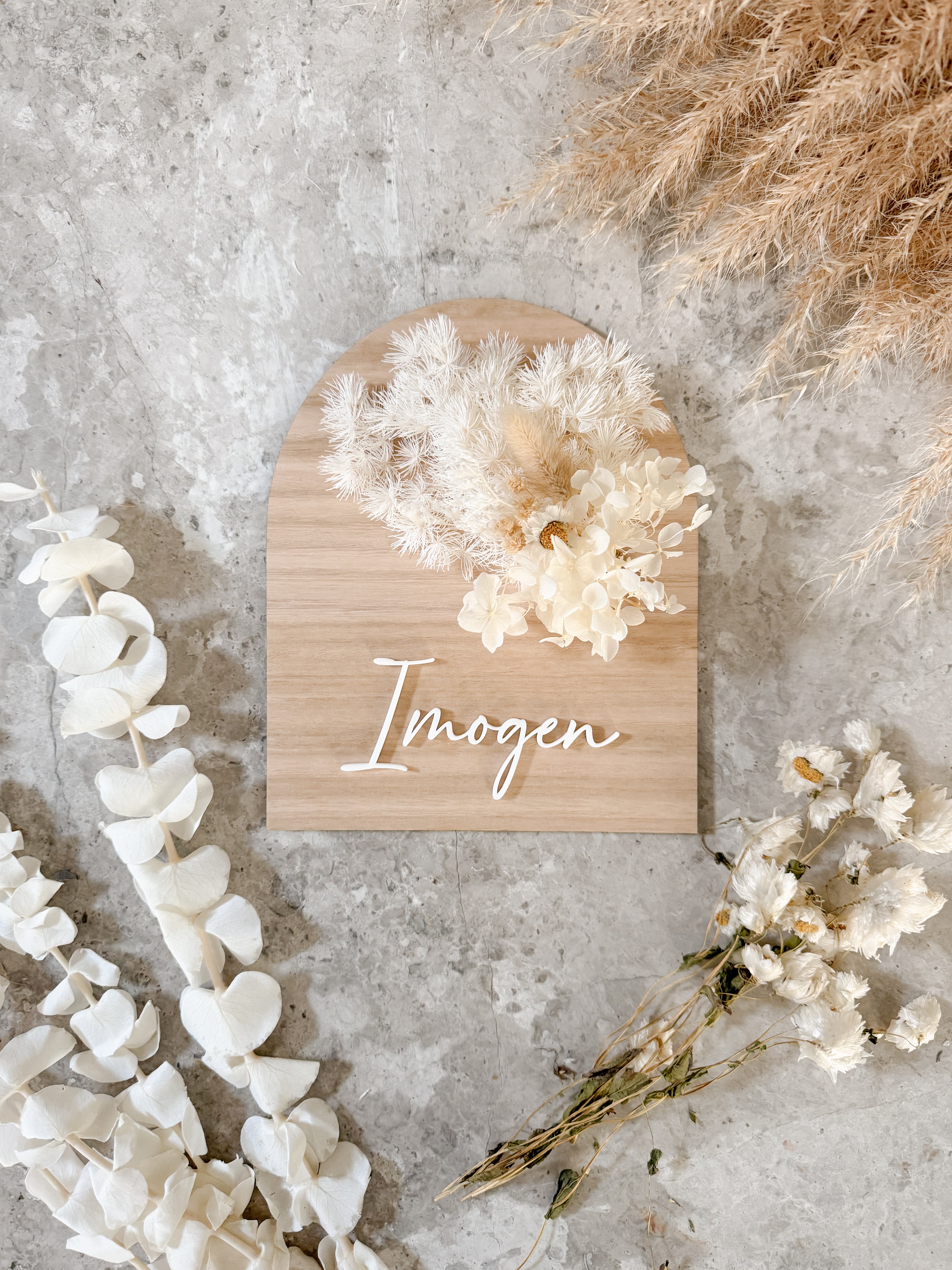 Dried floral wooden plaque with acrylic and/or laser engraved text or name, either arch or round shape, with dried preserved flowers tied to the plaque. Perfect for baby birth announcements or personalised gifts or keepsakes.