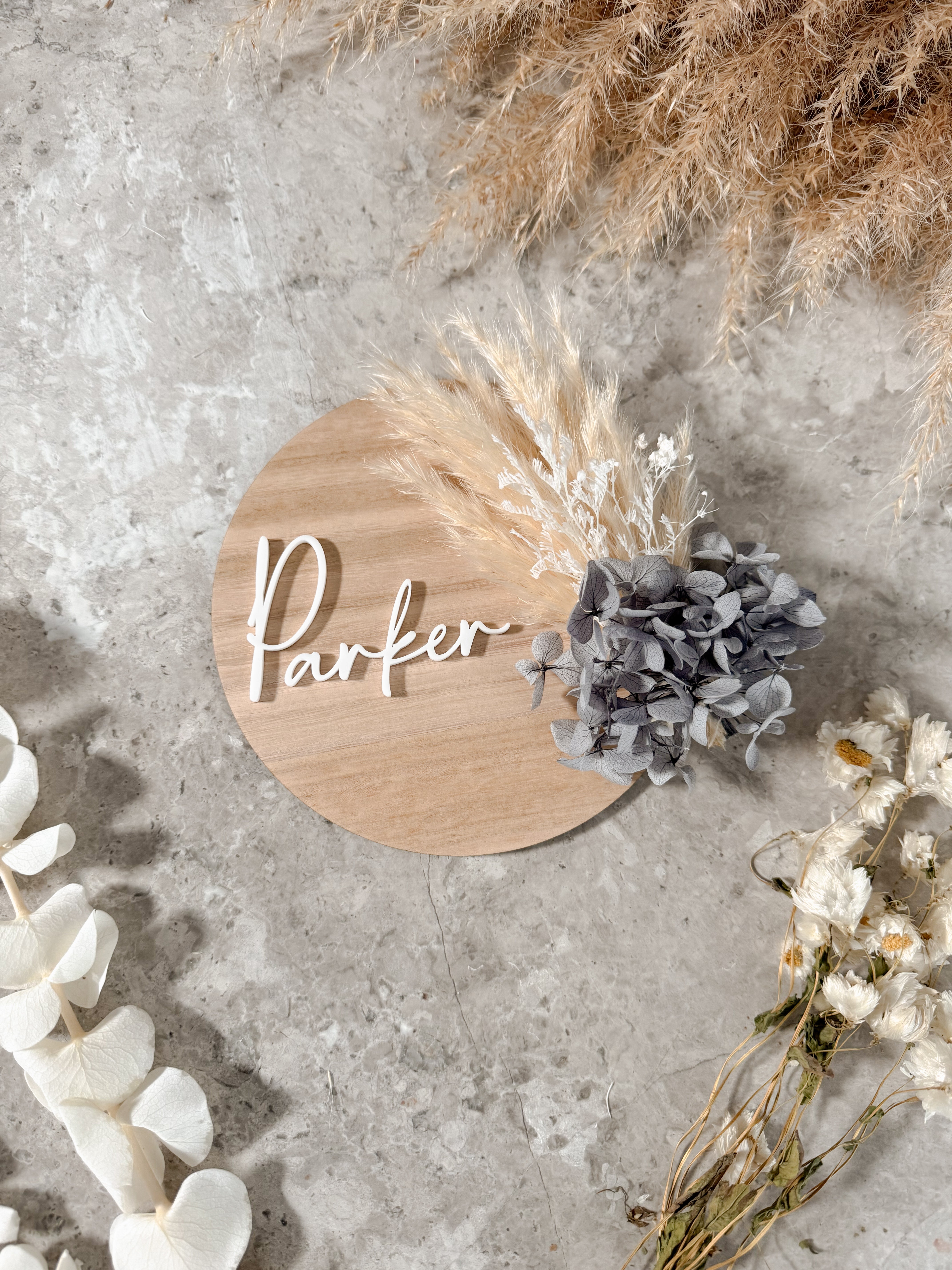 Dried floral wooden plaque with acrylic and/or laser engraved text or name, either arch or round shape, with dried preserved flowers tied to the plaque. Perfect for baby birth announcements or personalised gifts or keepsakes.