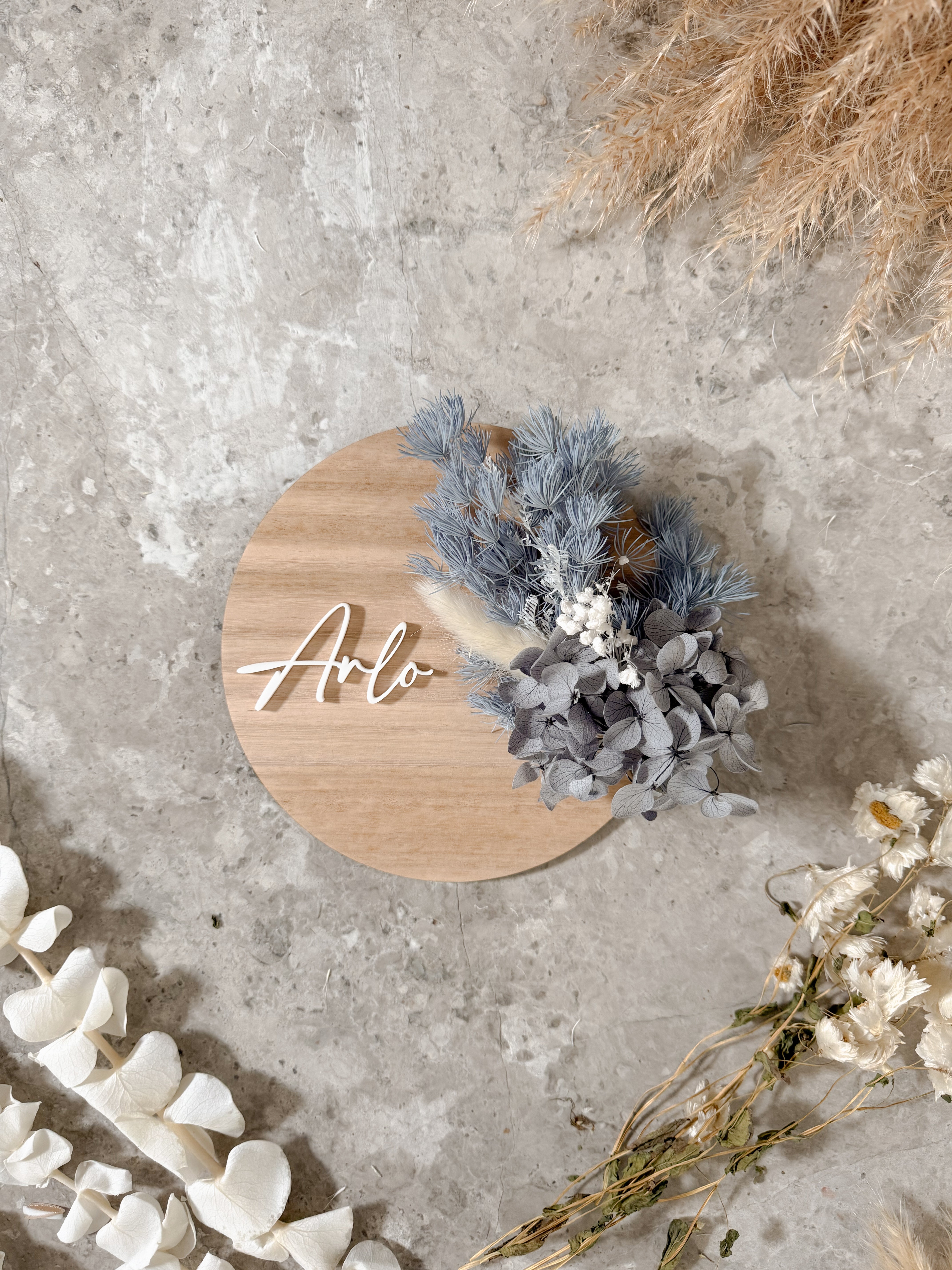 Dried floral wooden plaque with acrylic and/or laser engraved text or name, either arch or round shape, with dried preserved flowers tied to the plaque. Perfect for baby birth announcements or personalised gifts or keepsakes.
