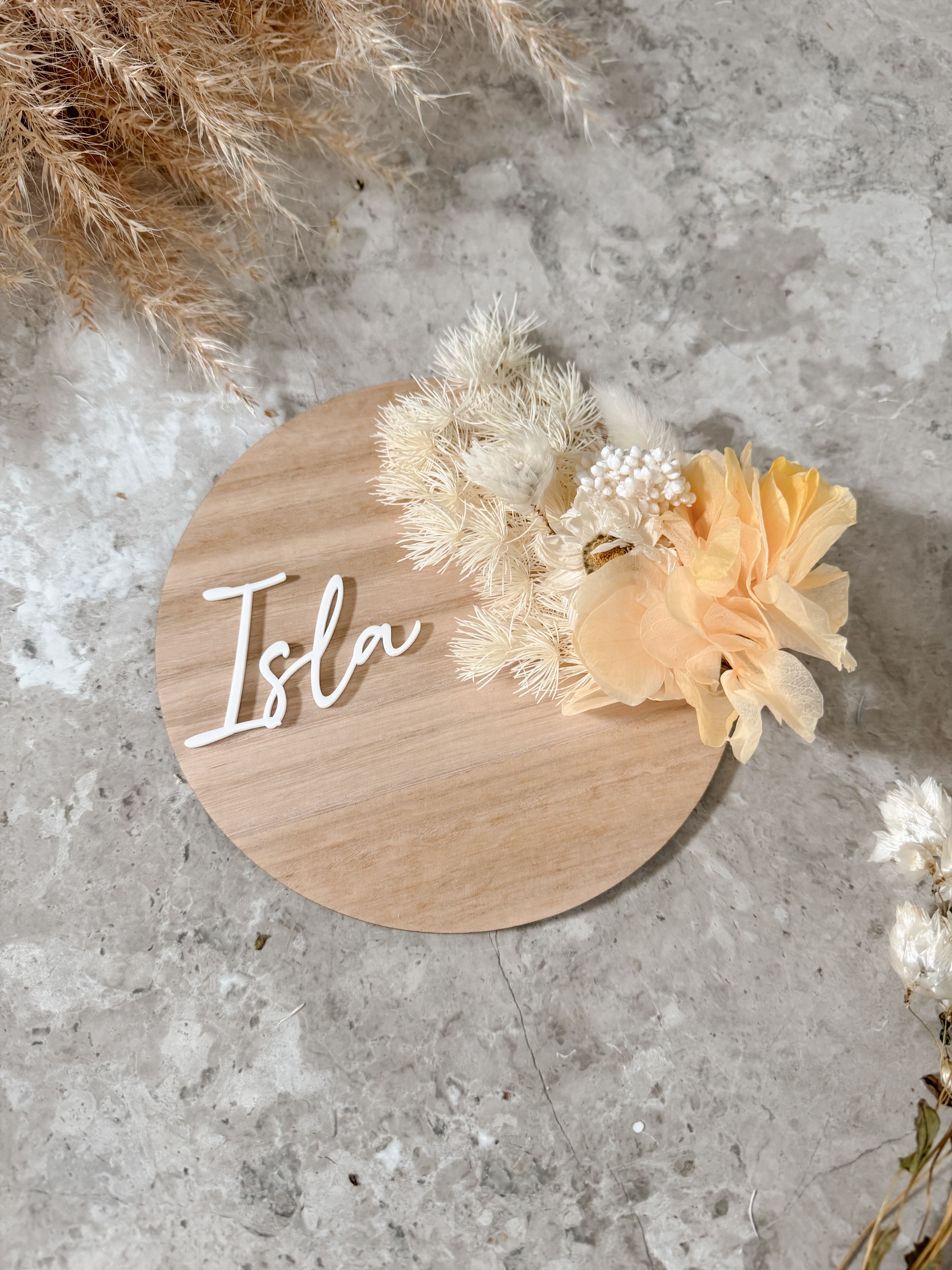 Dried floral wooden plaque with acrylic and/or laser engraved text or name, either arch or round shape, with dried preserved flowers tied to the plaque. Perfect for baby birth announcements or personalised gifts or keepsakes.