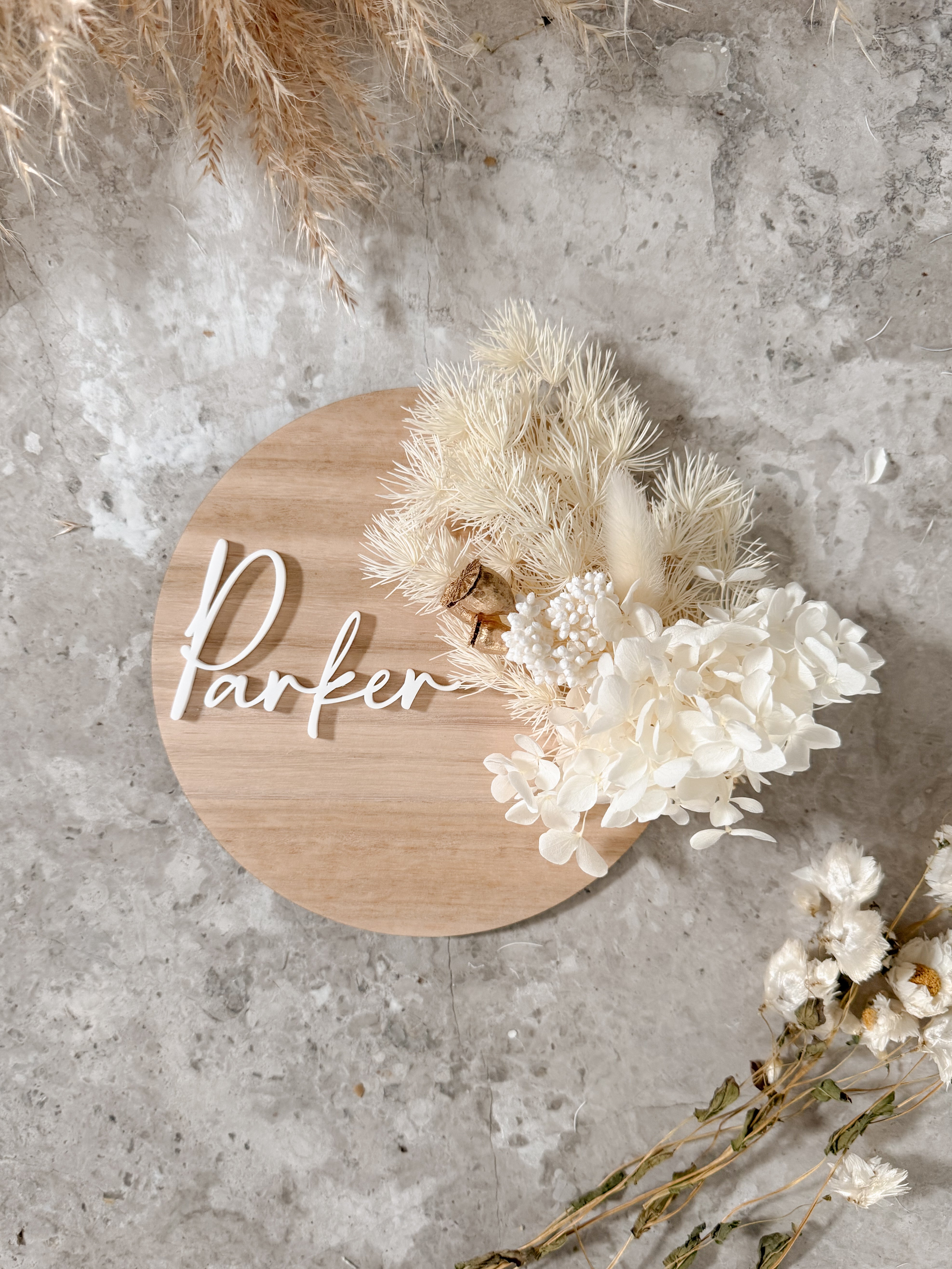 Dried floral wooden plaque with acrylic and/or laser engraved text or name, either arch or round shape, with dried preserved flowers tied to the plaque. Perfect for baby birth announcements or personalised gifts or keepsakes.