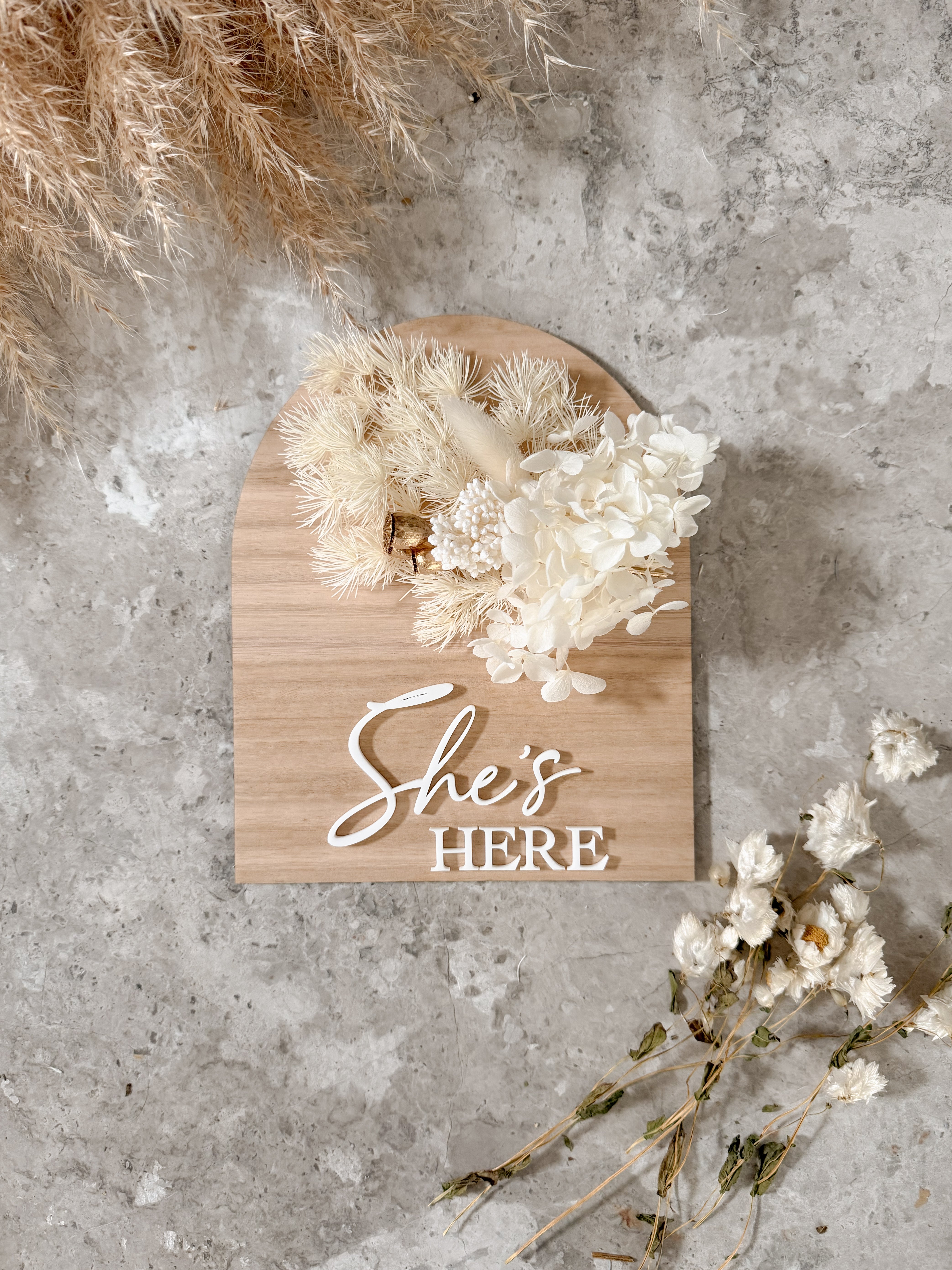 Dried floral wooden plaque with acrylic and/or laser engraved text or name, either arch or round shape, with dried preserved flowers tied to the plaque. Perfect for baby birth announcements or personalised gifts or keepsakes.