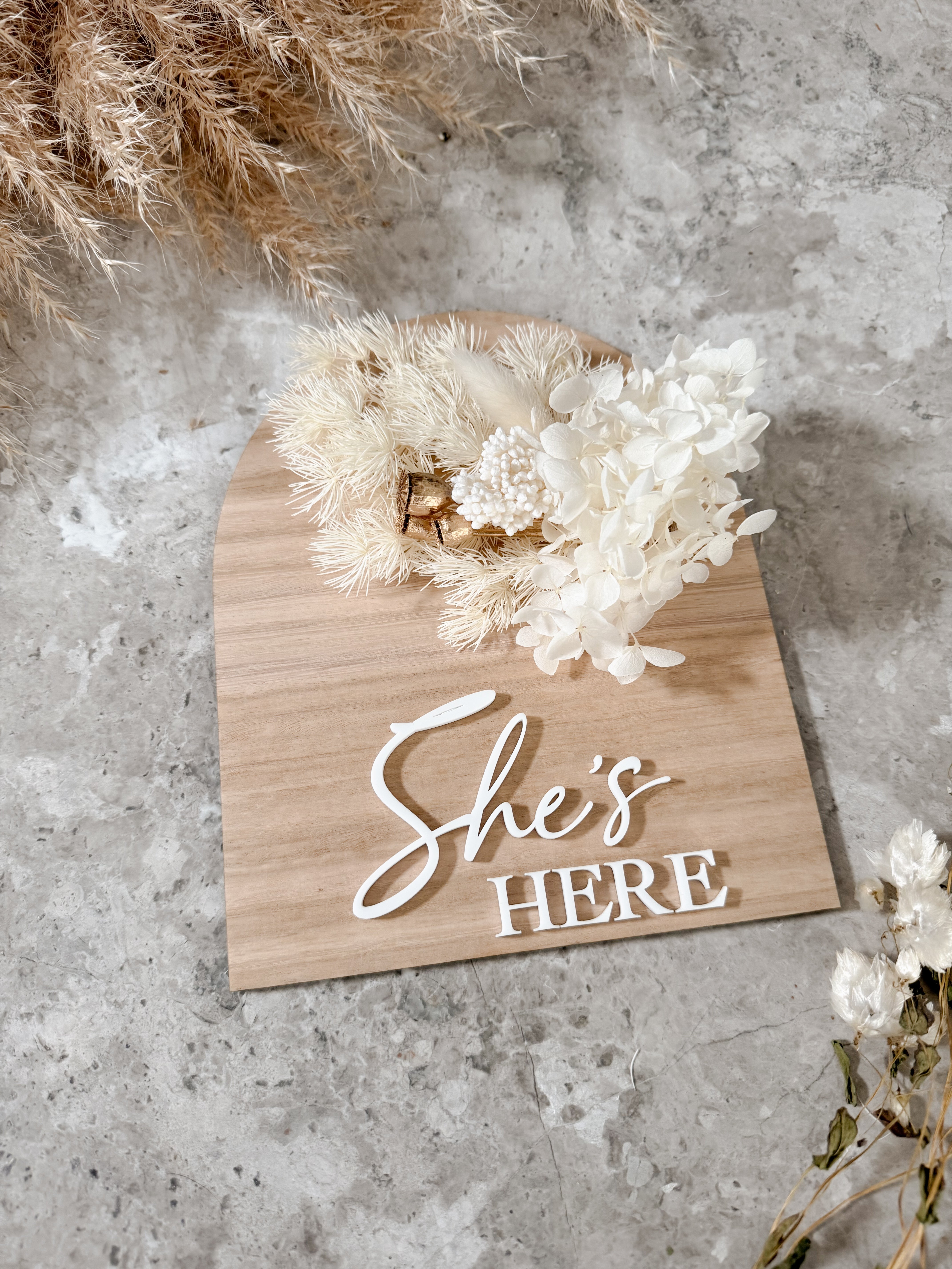 Dried floral wooden plaque with acrylic and/or laser engraved text or name, either arch or round shape, with dried preserved flowers tied to the plaque. Perfect for baby birth announcements or personalised gifts or keepsakes.