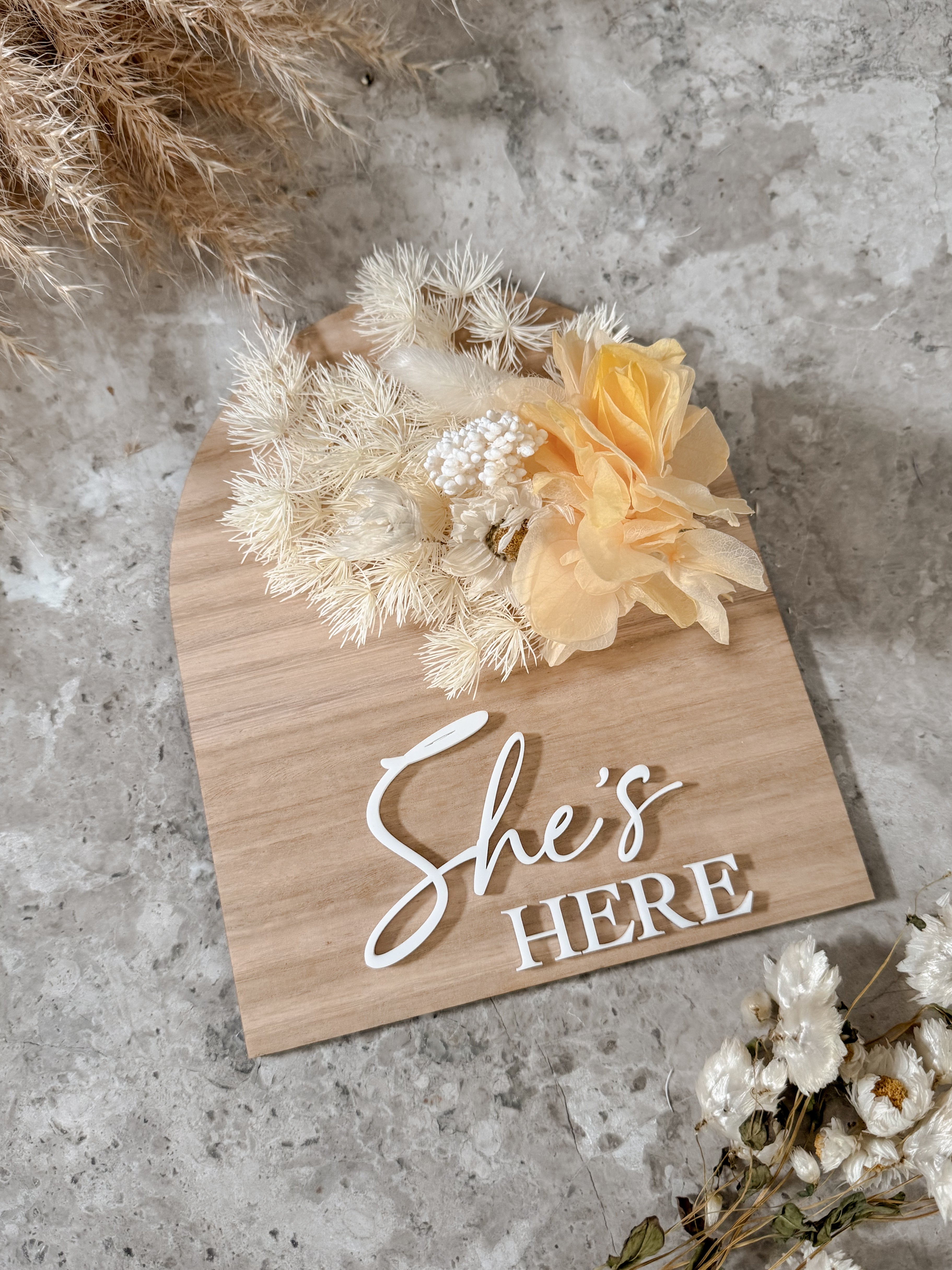 Dried floral wooden plaque with acrylic and/or laser engraved text or name, either arch or round shape, with dried preserved flowers tied to the plaque. Perfect for baby birth announcements or personalised gifts or keepsakes.