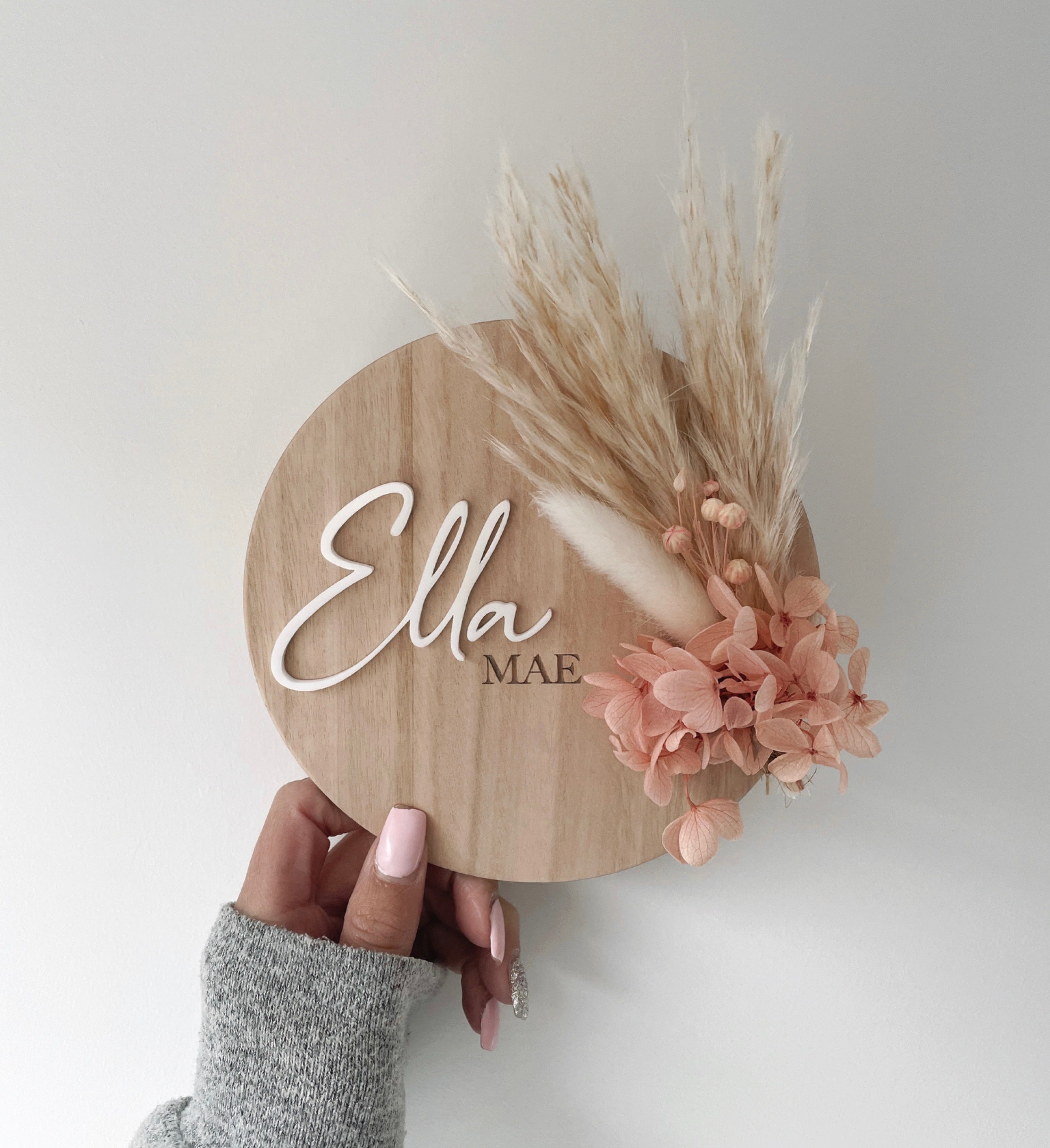 Dried floral wooden plaque with acrylic and/or laser engraved text or name, either arch or round shape, with dried preserved flowers tied to the plaque. Perfect for baby birth announcements or personalised gifts or keepsakes.